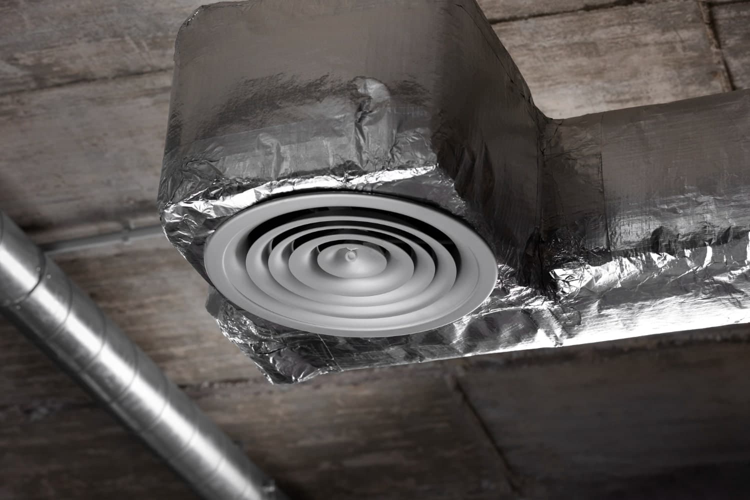 Clean visible air duct with a round ceiling diffuser inside a professional building.
