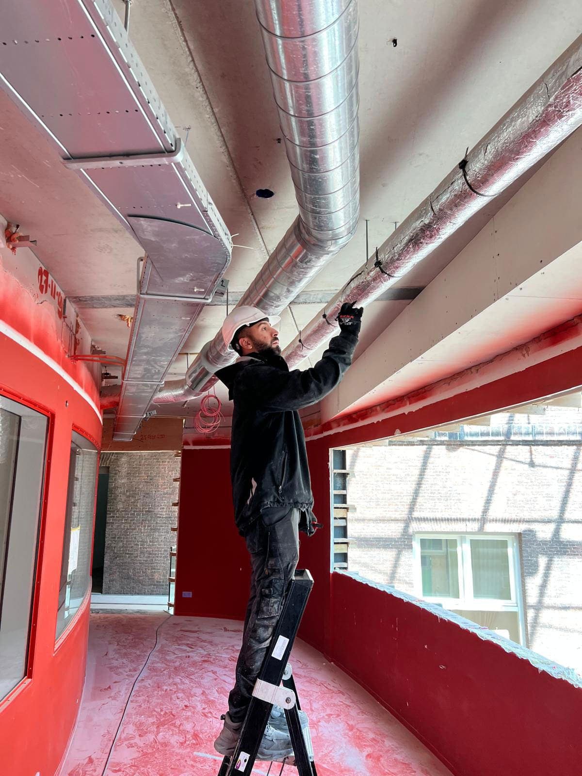 Technician working on visible ventilation ducts in a professional environment.
